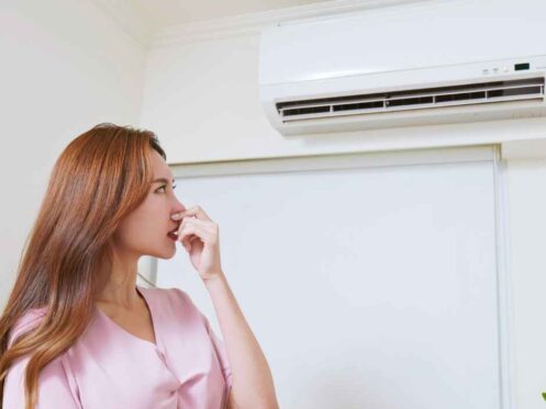A woman looking at her smelly air conditioner